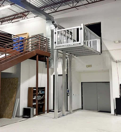 Industrial space with a staircase and a silver platform lift, showcasing a modern home elevator system for enhanced accessibility.